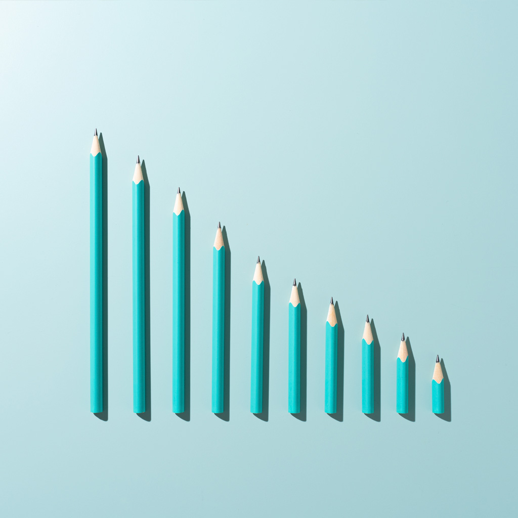 Ten blue pencils, side by side, with different heights, going down by length in descending order Ten blue pencils, side by side, with different heights, going down by length in descending order