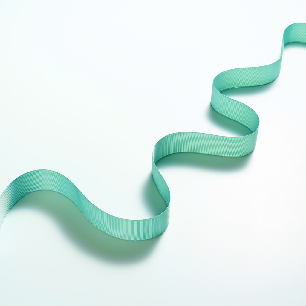Blue curly ribbon, starting at the bottom left of the image, and ending up the top right, on a white background Blue curly ribbon, starting at the bottom left of the image, and ending up the top right, on a white background