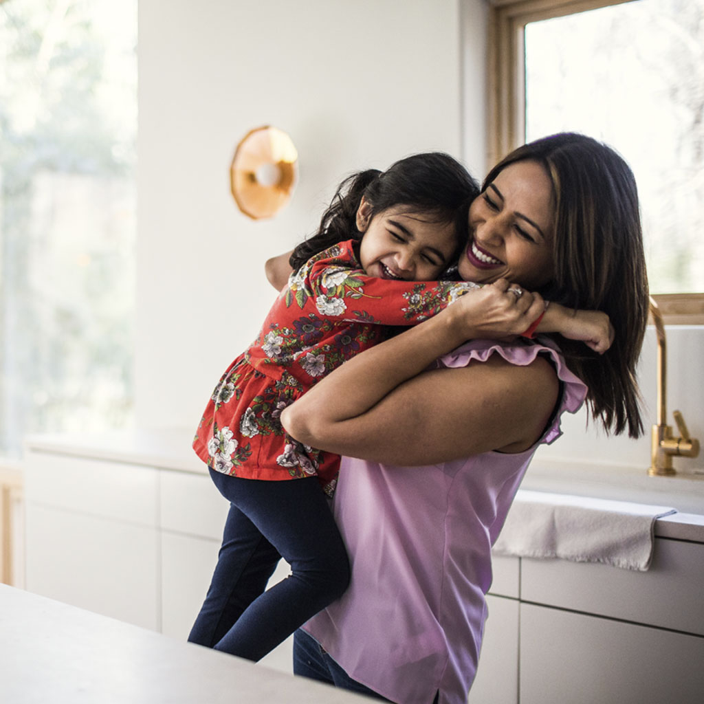 mum and young daughter sharing a hug in a white and light kitchen mum and young daughter sharing a hug in a white and light kitchen