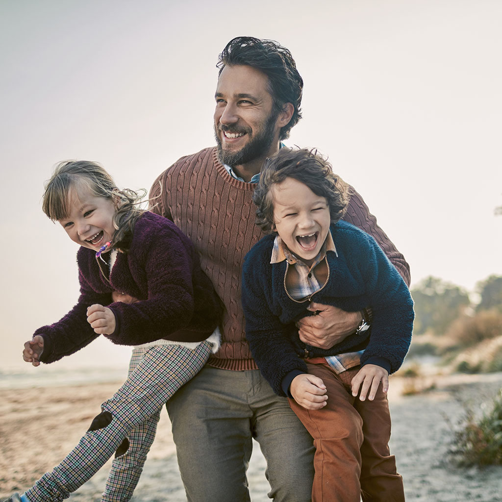 dad holding his two sons under his arms, on a sunny beach dad holding his two sons under his arms, on a sunny beach