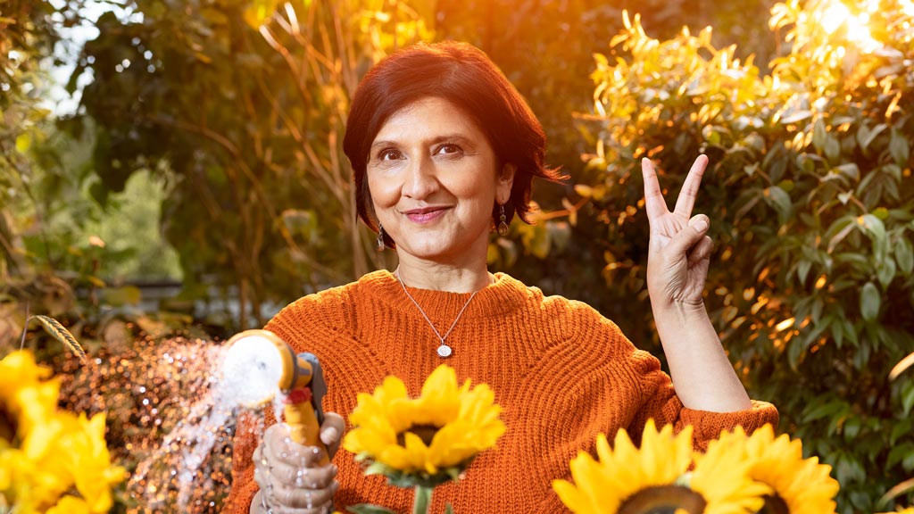 Older Asian lady wearing an orange jumper making the 'peace' sign with her left hand Older Asian lady wearing an orange jumper making the 'peace' sign with her left hand