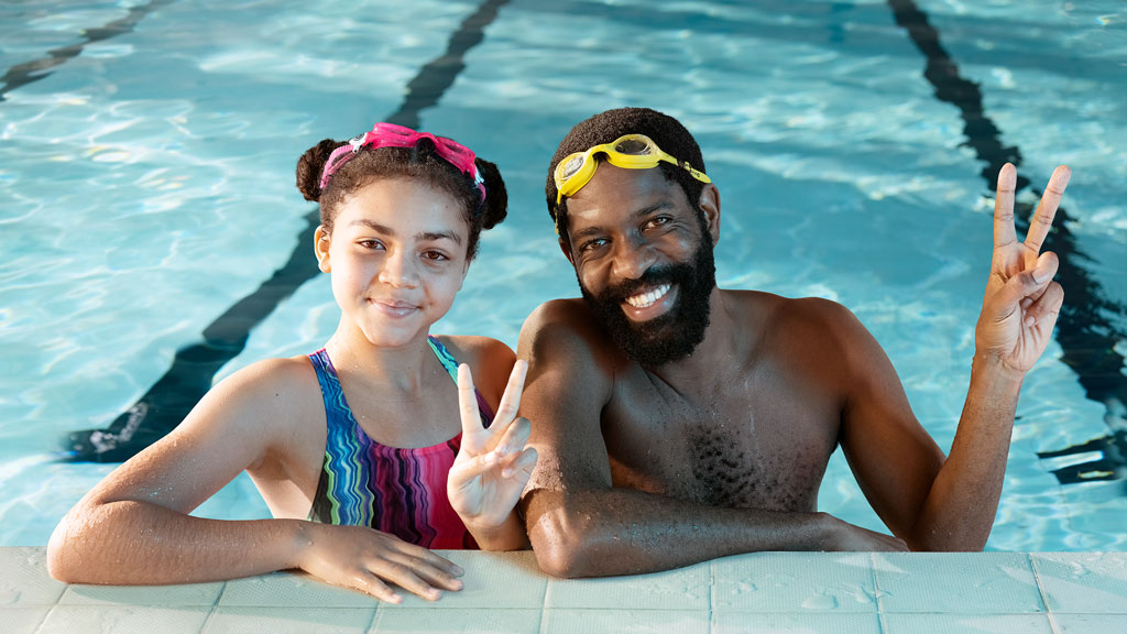 Father and daughter wearing goggles in a swimming pool Father and daughter wearing goggles in a swimming pool