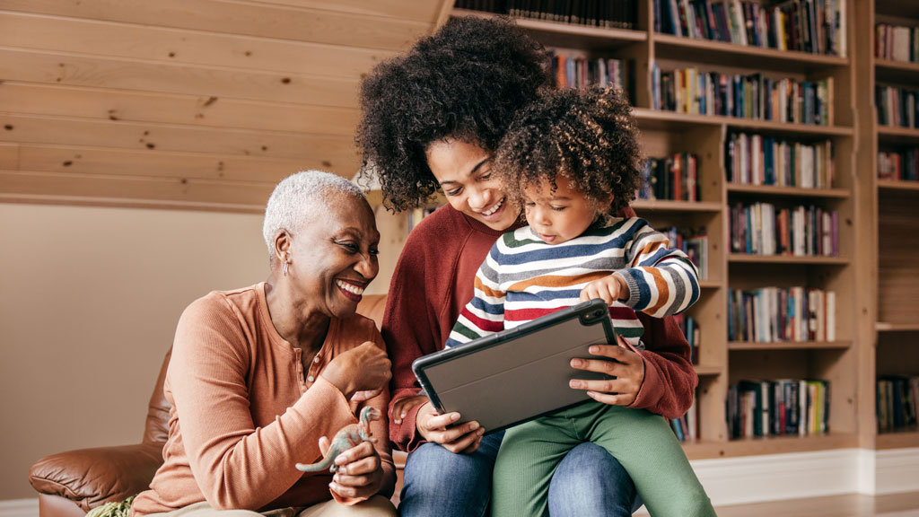 Laughing intergenerational family looking at a tablet together Laughing intergenerational family looking at a tablet together