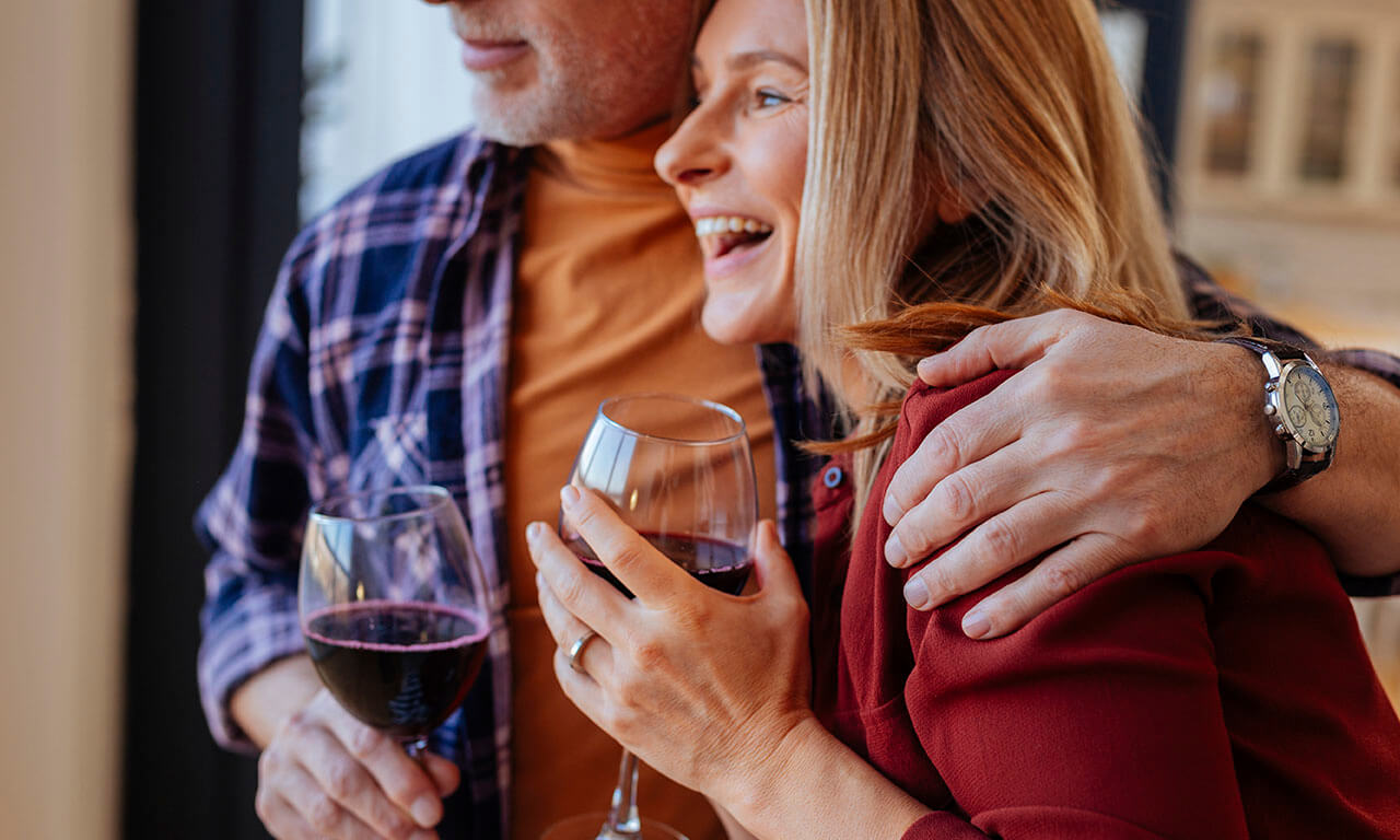 Smiling couple drinking red wine together and laughing